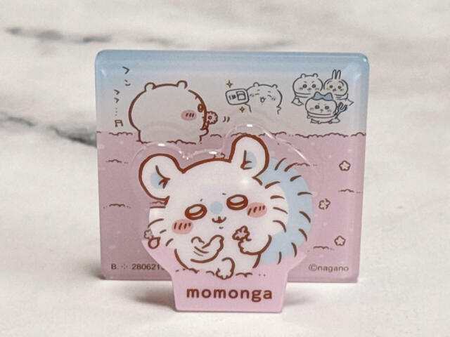 【ちいかわ アクリルシーンクリップビスケット】花占いをするちいかわから花を横取りし、真似をするモモンガ。背景のちいかわの姿も愛らしいです♪